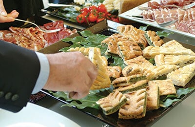 Employees getting for from a gourmet lunch spread